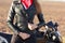 Cropped image of sporty woman zips her black leather jacket, prepares for racing competiotns or marathon, poses near motorbike,