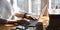 Cropped image of stylish woman typing on computer laptop while sitting at the wooden working desk.