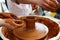 Cropped Image of Unrecognizable Female Ceramics Maker working with Pottery Wheel in Cozy Workshop Makes a Future Vase or