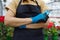 Cropped image of unrecognizable female gardener in apron with pruner in hand.