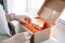 Cropped image of woman hands packing shipment with silicone kids dishes in box for delivery, checking quality of package