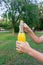 Cropped image of a woman while opening a cold bottle of lemonade in a hot day in the park