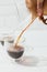 Cropped image of woman pouring alternative coffee from chemex into glass mug