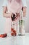 cropped image of woman putting tomatoes in glass jar with water