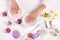 cropped image of woman receiving bath for nails at table with flowers, colorful sea salt, cream container, aroma oil bottles and