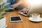 Cropped image young man sitting at the table with cup of coffee, digital tablet and computer,