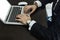 Cropped image of a young man working on his laptop rear view of business man hands busy using laptop at office desk