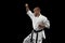 Cropped image of young professional karate fighter training isolated over black background