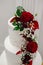Cropped images of beautiful modern white wedding cake decorated with fresh red roses with copy space.