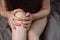 Cropped images of unrecognizable woman sitting on bed at home with knee pain, young woman massaging her painful knee