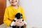 Cropped indoor image of a smiling broadly happy child playing at home with a little dog. Cute little girl cares about the puppy.