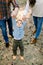 Cropped outdoor shot of happy family in stylish casual clothes, playing and having fun in autumn pine forest, holding