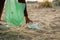 Cropped photo of African woman collecting spilled trash from sand on beach in green plastic bag. Ecology, pollution.