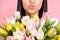 Cropped photo portrait of girl sending air kiss keeping tulips bouquet on 8 march isolated pastel pink color background