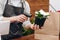 Cropped photo of saler scanning bar code of flowerpot. Flowers delivery service and sale of home plants in pots, wooden showcase
