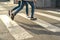 Cropped photo of two people in jeans running across the road. Crosswalk