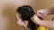 Cropped photo of woman mother weaving braid using artificial strand of black yellow kanekalon in long dark hair of girl.