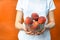 Cropped photo of young woman in white t-shirt casual outfit wear hold glass crystal transparent bowl of peaches isolated on orange