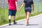 Cropped  picture of two young adults wearing shorts and tee shirts on paved walking trail with fingers intertwined - cropped and