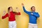 Cropped portrait of cheerful couple, man and woman dancing isolated over yellow background. Celebration