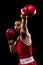 Cropped portrait of one professional boxer in red uniform training isolated over black background. Punching
