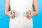 Cropped portrait of pregnant woman holding cubes which show thirty weeks of pregnancy at blue background. Healthy pregnancy. Copy