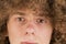 Cropped portrait of a young curly European man with long curly hair and a defiant gaze looks into the frame close-up. very lush