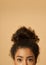 Cropped portrait of young mixed race woman with highly raised dark curly hair looking at camera while posing isolated