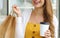 Cropped portrait of young stylish lady with shopping bags holding paper cup of coffee showing brand name