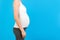 Cropped potrait of pregnant belly in home clothing at blue background. Woman is expecting a baby. Copy space