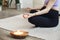 Cropped pregnant woman sitting in yoga position in spa room, focus on coco candle, relaxing and meditating