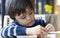 Cropped shot Active child reading a books on the table in the cafe while waiting for food, Cute little boy with curious face try t