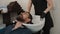 Cropped shot of barber washing hair to bearded man in barbershop