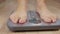 Cropped shot of barefoot woman controlling his weight on scale