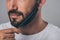 cropped shot of bearded man combing beard with comb