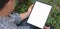 Cropped shot of businessman working on his project with blank screen tablet with garden background