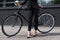 cropped shot of businesswoman in suit with disposable cup of coffee standing near retro bicycle