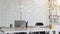 Cropped shot of co working space with laptop, office supplies, and coffee cup on white desk with blurred office room