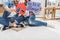 Cropped shot of couple sitting on floor and showing sign with our first