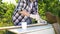 Cropped shot of crafts woman painting wooden plank with white paint in garden