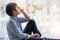 Cropped shot of depressed man sitting on the floor by window at office walkway feeling unhappy. Depression and anxiety disorder