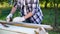 Cropped shot of female carpenter measures wooden plank with measuring tape