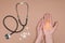 cropped shot of female hands with ribbon, pills and stethoscope on beige tabletop, world health day concept