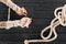 cropped shot of female tattooed hands tied in rope on dark wooden tabletop