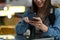 Cropped shot of female traveller using smart phone while sitting at outdoor street food restaurant