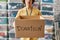 Cropped shot of a guy holding donation box, posing in front of boxes full of clothes, Young male volunteer working for a