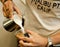 Cropped shot of hand of barista making. Focus on hands holding c