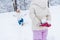 cropped shot of little daughter holding snowballs and happy mother kneeling behind in winter park