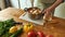 Cropped shot of man, chef cook using hand blender, blending chopped vegetables and bread while preparing Italian meal in