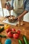 Cropped shot of man, chef cook using hand blender, blending chopped vegetables and bread while preparing Italian meal in